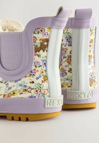 Blumenmuster Gummiregenstiefel in Creme und Lavendel, mit einer strukturierten Sohle, gepolstertem Innenbereich und Markenakzenten.