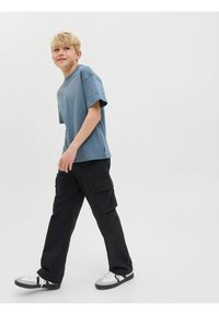 T-shirt en coton bleu à manches courtes, associé à un pantalon cargo noir avec plusieurs poches et des baskets blanches avec des accents gris.