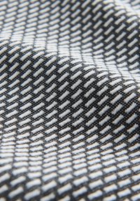 Zwart-wit textiel met een chevronpatroon. De stof heeft een gestructureerde weving met afwisselende horizontale en verticale lijnen.