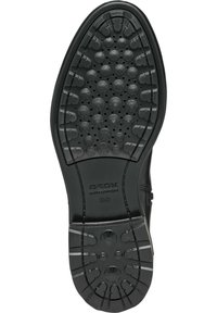 Suela de zapato negra con una superficie texturada y con patrón que presenta formas circulares y estelares. Marcada con "GEOX" y "ULTRA COMFORT."