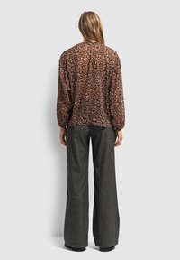 Blouse met dierenprint in doorzichtig materiaal, met een bruin en zwart luipaardpatroon. Losse fit met elastieken manchetten en een ronde onderkant.