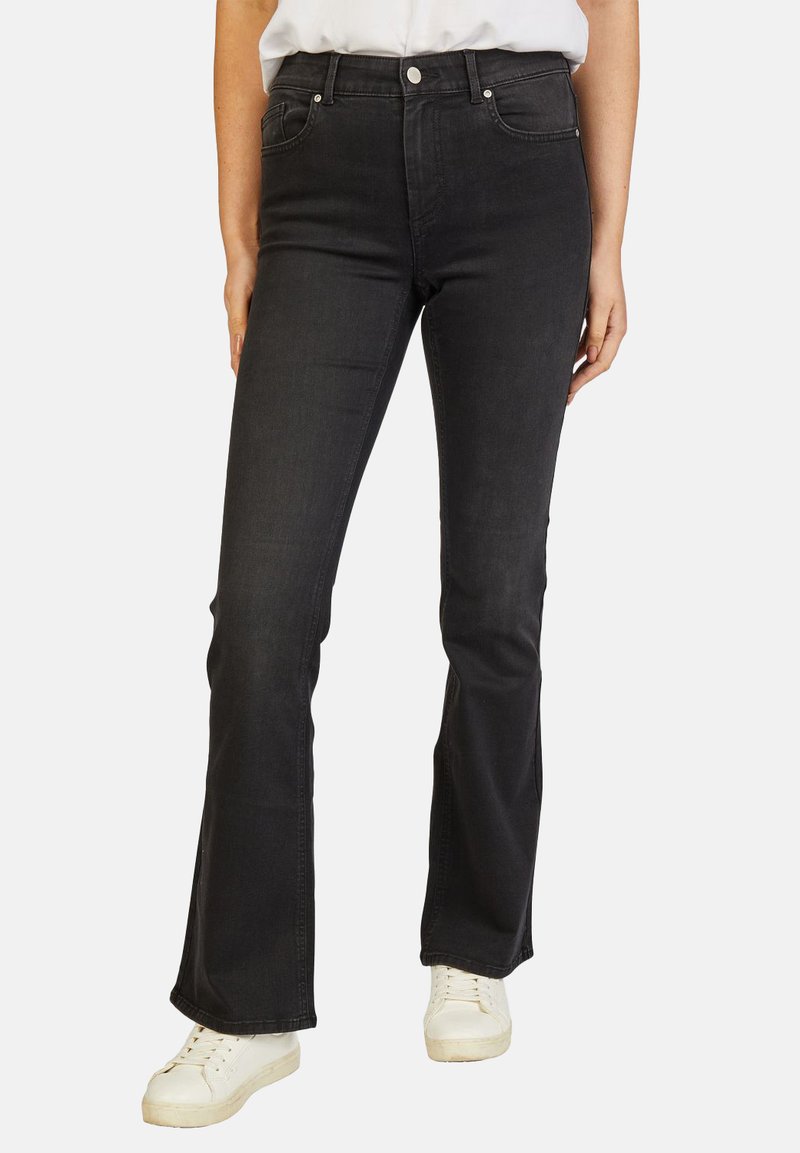 Zwarte flared jeans van denim, met een hoge taille, vijf zakken en subtiele stikdetails, gecombineerd met witte sneakers.