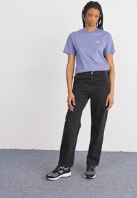 Paarse katoenen t-shirt, zwarte rechte jeans en zwarte sport sneakers. Eenvoudig ontwerp, geen zichtbare patronen of accenten.