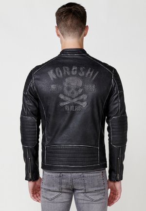 Chaqueta de motocicleta de cuero negro con acentos acolchados, diseño de calavera en relieve y puños con cremallera. Costuras reforzadas en toda la prenda.