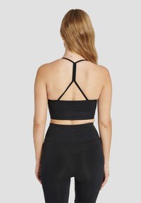 Zwart sportief crop top met dunne bandjes en een aansluitend ontwerp. Gladde textuur met een brede band aan de onderkant en een racerbackstijl.