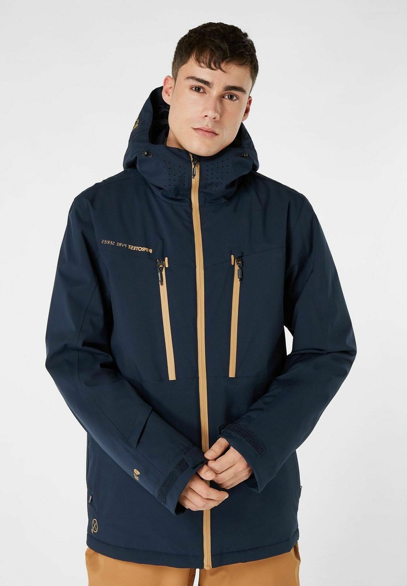 Giacca impermeabile blu navy con un ampio cappuccio, dettagli in beige per la zip e le tasche, area delle spalle texturizzata e polsini regolabili.
