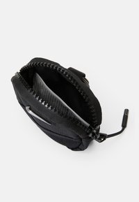 Fekete nylon tasak cipzárral, amely textúrált felülettel és egy kis belső zsebbel rendelkezik. Könnyű hozzáférést biztosító húzófüllel van ellátva.