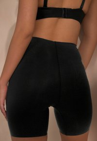 Shorts da ciclismo neri a vita alta realizzati in un tessuto morbido e elasticizzato. Presentano un design aderente con una cucitura verticale al centro sul retro.