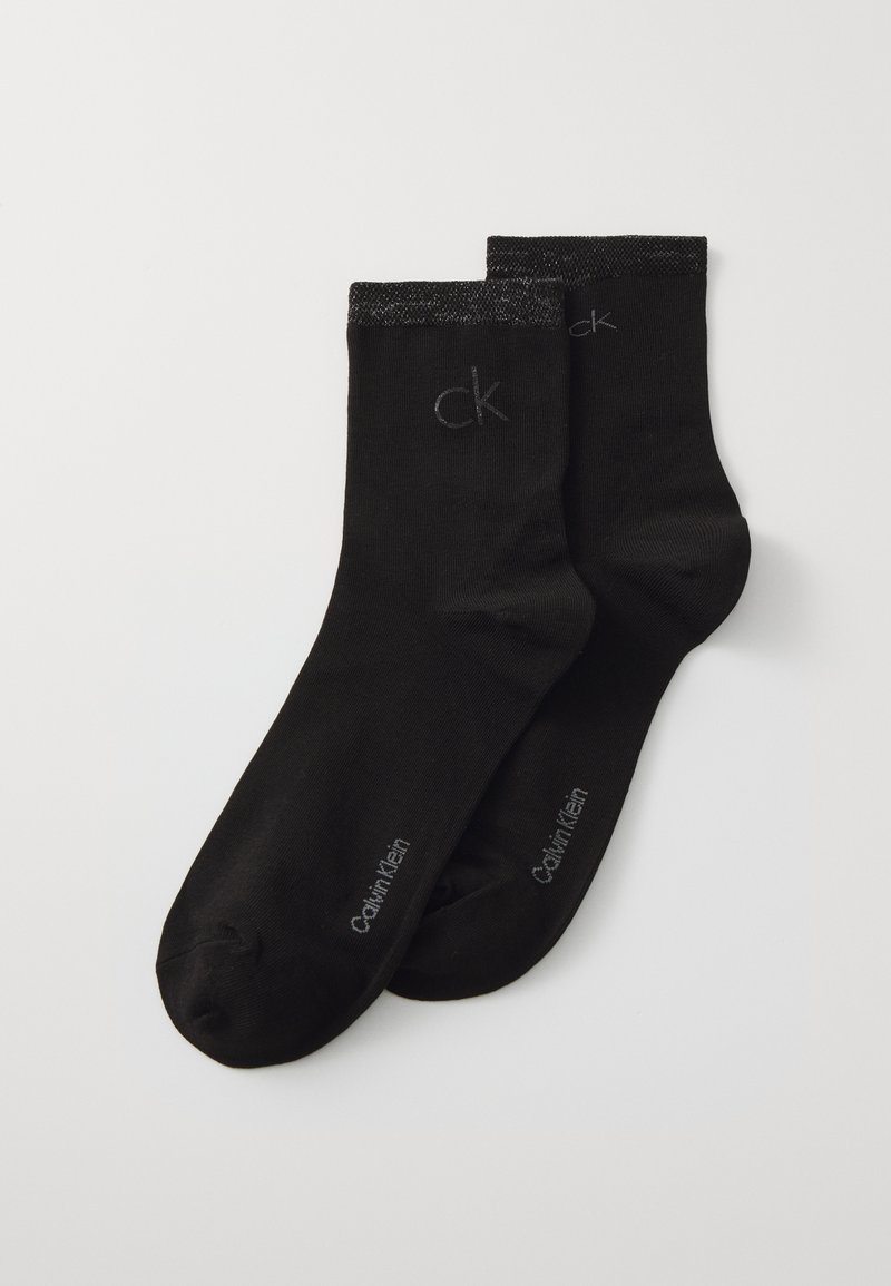 Mustmustest puuvillased sokid, millel on sile tekstuur. Ülemises osas on kontrastne tume riba ning trükitud "Calvin Klein" ja "ck" logod.