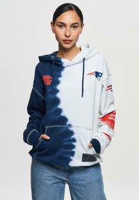 Sweatshirt à capuche avec un motif tie-dye bleu à blanc, logos brodés, poche kangourou et poignets côtelés. Tissu en mélange de coton.