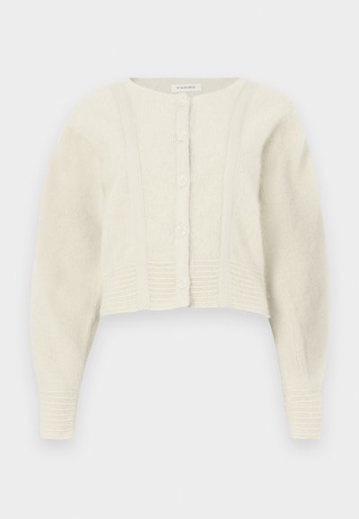 Cardigan corto color marfil claro hecho de punto suave con cuello redondo, cierre frontal con seis botones y detalles acanalados en los puños y el dobladillo.