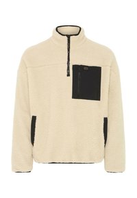 Sudadera de forro polar en color crema con detalles en negro. Cuenta con un cuello con media cremallera, un bolsillo en el pecho y bolsillos laterales. Material suave y texturizado.