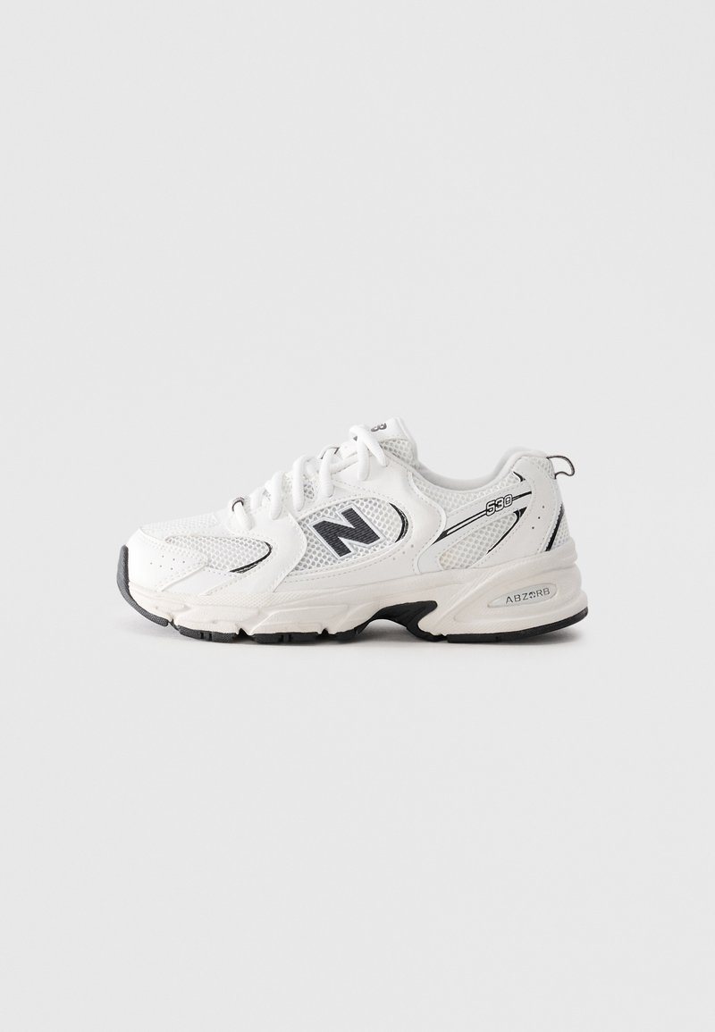 Sneaker New Balance 530 blanc avec accents noirs, panneaux en maille, lacets et semelle rembourrée sur un fond gris clair unicolore.
