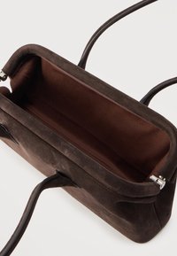 Καφέ σουέντ τσάντα χειρός με δερμάτινες λαβές, ανοιχτό πάνω μέρος που αποκαλύπτει εσωτερικό από λείο ύφασμα και μηχανισμό κλεισίματος από ασημένιο.