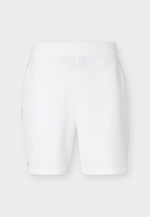 Fehér térdig érő rövidnadrág lapos derékpánttal és oldalzsebekkel, sima világos háttér előtt bemutatva.