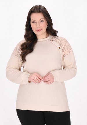 Pulover bej cu textură în relief, detaliu din dantelă pe umeri și două butoane decorative. Mâneci lungi și decolteu tip crew. Pantaloni negri.