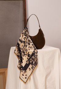 Brun ruskindshåndtaske med en buet form og et kort håndtag, pyntet med et cremefarvet silketørklæde med leopardprint og sort kant.