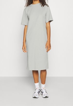 Grå bomulls t-shirtklänning med korta ärmar, rak skärning, knälång, bärs med vita sportskor och vita strumpor.