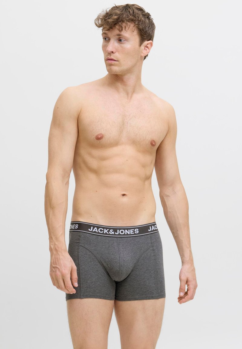 Sive bokserice s crnim elastičnim pojasom na kojem piše 'JACK & JONES'. Materijal izgleda glatko i rastezljivo. Model je bez majice.