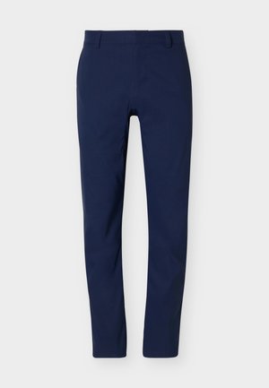 Στενά παντελόνια σε ναυτικό μπλε χρώμα με θηλιές για ζώνη και εμπρόσθιο κλείσιμο με φερμουάρ πάνω σε λευκό φόντο.