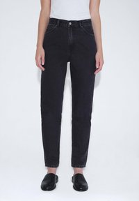 Schwarze Jeans aus Denim mit hoher Taille, schmaler Passform, fünf Taschen, sichtbaren Nähten und einem Knopfverschluss. Glatte Textur und schmal zulaufendes Bein.