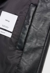 Interno di giacca di pelle nera con etichetta slim fit e tasca. Caratterizzato da una texture liscia e una fodera in raso a contrasto.