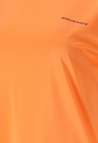 Orange idrottströja i mjukt, lätt material. Har en subtil textur med en svart "ENDURANCE"-logotyp på bröstet.