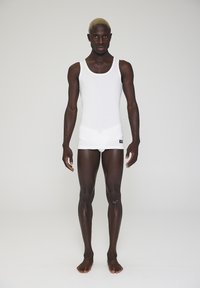 White tank top and matching shorts made of smooth, stretchy fabric, fitted design highlighting the body shape. No visible patterns or accents.