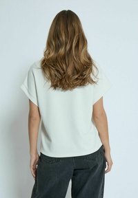 Top corto grigio chiaro a maniche corte con una vestibilità morbida, abbinato a pantaloni a gamba larga grigio scuro; tessuto liscio, cuciture minime e spalle calate.