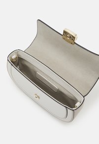 Rektangulär handväska i krämfärgad läder med texturerad yta. Guldspänne, beige mockafoder och svart kantdetaljering. Inre etikett synlig.