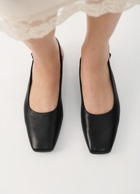 Ballerines noires en cuir, avec un bout carré et une texture lisse. Dotées d'un petit talon et d'un design minimaliste, parfaites pour de nombreuses tenues.