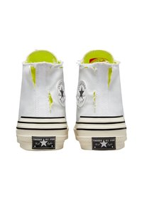 Bílé plátěné vysoké tenisky se zkoseným vzhledem, neonově žluté podšívce, černými pruhy na podešvi a černou nášivkou All Star.