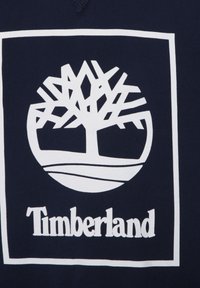 Felpa navy con logo Timberland bianco, caratterizzato da un albero stilizzato e un design circolare, che mette in risalto linee e forme geometriche.