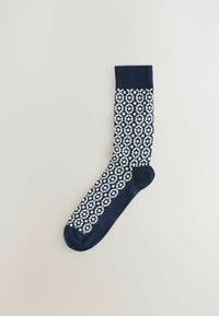 Calcetín azul marino con patrón geométrico blanco, puño acanalado, textura suave, forma alargada y pie sólido azul marino.
