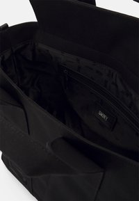 Borsa tote nera in tela con un ampio interno. Tessuto testurizzato, dotata di una tasca con cerniera e fodera con logo ripetuto.