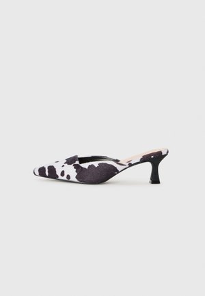 Špičaste slingback pete v črno-beli kravji vzorec. Zgornji del iz tkanine z teksturirano površino in tanek črn pet.