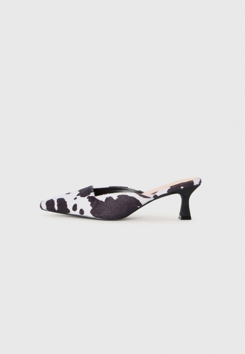 Talons slingback à bout pointu en design imprimé vache noir et blanc. Tige en tissu avec finition texturée et un fin talon noir.
