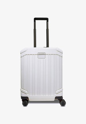 Valise rigide blanche avec rainures verticales, poignée noire et quatre roues ; comprend une plaque avec logo à l'avant.