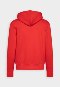 Punainen huppari, jossa on sileä ja teksturoitu kangas. Ominaisuuksiin kuuluvat pitkät hihat, säädettävä huppu sekä resorit hihansuissa ja helmassa.