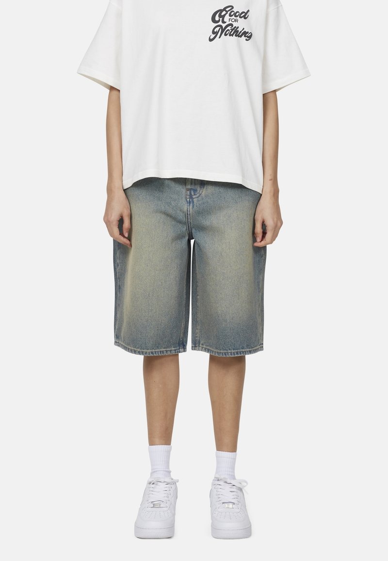 Shorts in denim azzurro chiaro con un effetto scolorito, presentano una vestibilità comoda. Abbinati a una t-shirt bianca con grafica e sneakers bianche.