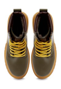 Botas de tobillo de cuero verde con cordones amarillos, suelas texturizadas y acentos marrones, que cuentan con un tirador en la parte trasera para facilitar el calzado.