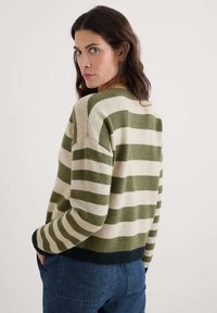 Maglione a righe nei colori verde e crema, con colletto rotondo, maniche lunghe e polsini e orlo a costine. Texture morbida, vestibilità rilassata.