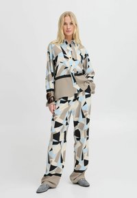 Knoop-shirt en wijde broek in geometrisch patroon met blauw, beige en zwart. Glad stof met lange mouwen en ontspannen pasvorm.