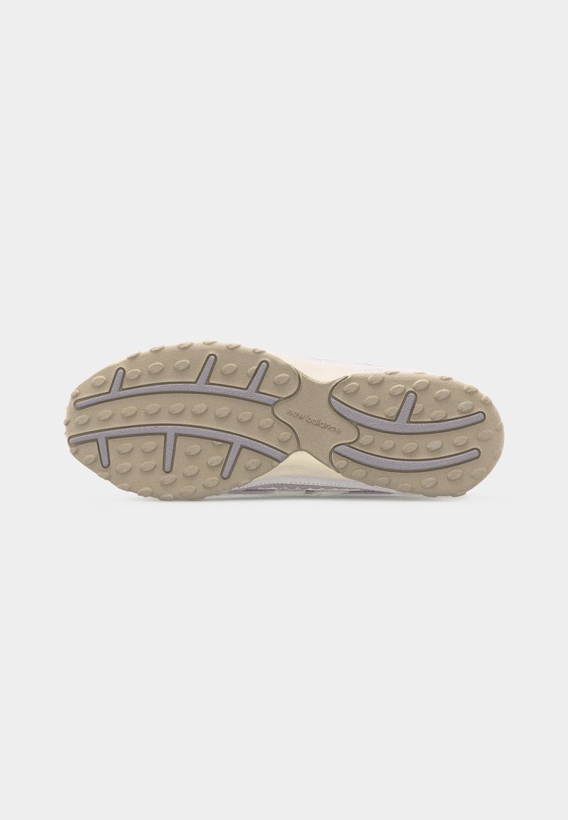 Suela de zapatilla de goma beige y gris clara con agarres ovalados texturizados y patrones de banda de rodadura ranurados sobre fondo blanco.