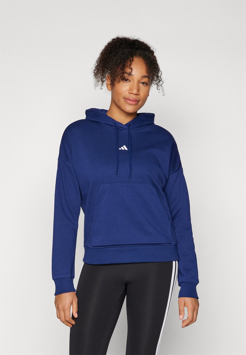Hoodie azul marinho feito de uma mistura de algodão, apresentando um bolso frontal, capuz com cordão e um logótipo branco no peito. Combinado com leggings pretas.