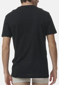 Svart bomulls t-shirt med korta ärmar, rundad halsringning och slät yta. Ingen synlig logotyp eller mönster; normal passform med rak fåll.