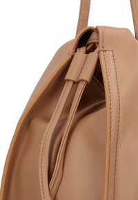 Tan leren tas met een zachte textuur, voorzien van een afgeronde vorm, decoratieve stiksels en een knoopsluiting.