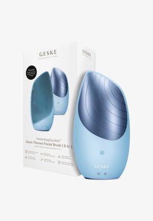 Lichtblauwe Sonic Thermo gezichtsborstel met gestructureerde voorkant en gladde achterkant, getoond naast een witte productdoos met merk en functies vermeld.