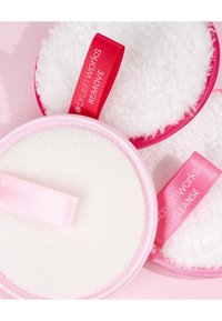 Conjunto de tres almohadillas faciales redondas en rosa y blanco, con diferentes texturas: tela suave, pelaje esponjoso y superficie lisa. Cada una cuenta con una correa con etiqueta.