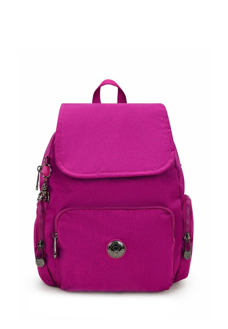 Sac à dos magenta avec une fermeture à rabat, comportant plusieurs poches zippées, une texture lisse, une poignée supérieure et un charm décoratif sur la fermeture éclair.